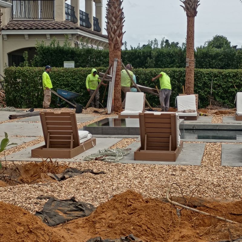 Crew installing irrigation and hardscape around a paver patio